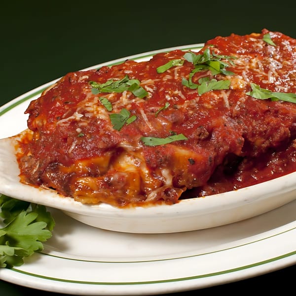 Tony & Alba's baked lasagna, topped with rich red sauce, melted cheese, and fresh parsley.